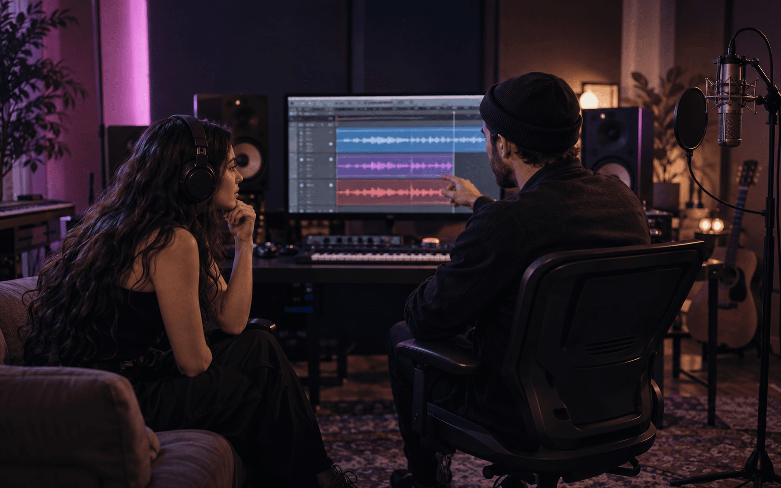 Two musicians reviewing separate vocal and instrument tracks on a studio screen